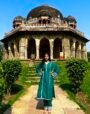 Woman wearing a teal green kurta set with matching pants and rainbow silver lace detailing in front of a historic monument