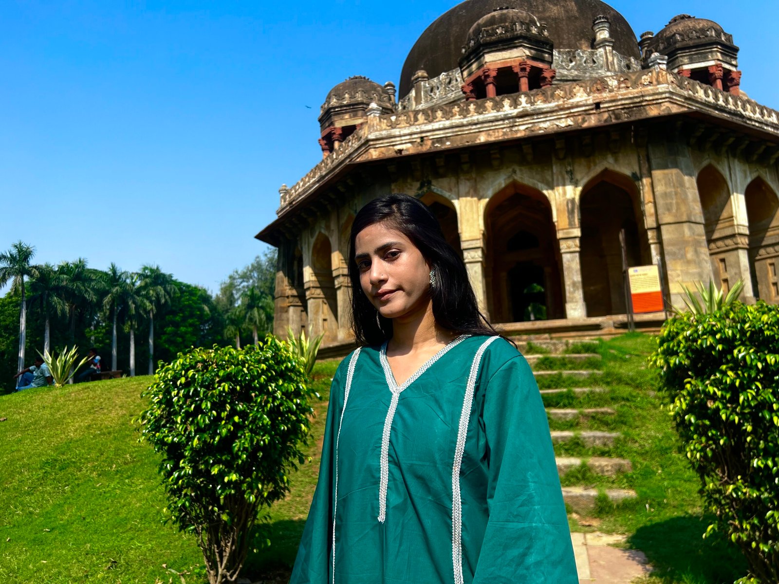 Teal Green Women's Kurta with Rainbow Silver Lace Trim Close-up view of a woman wearing a teal green kurta with a V-neckline and rainbow silver lace trim in a garden